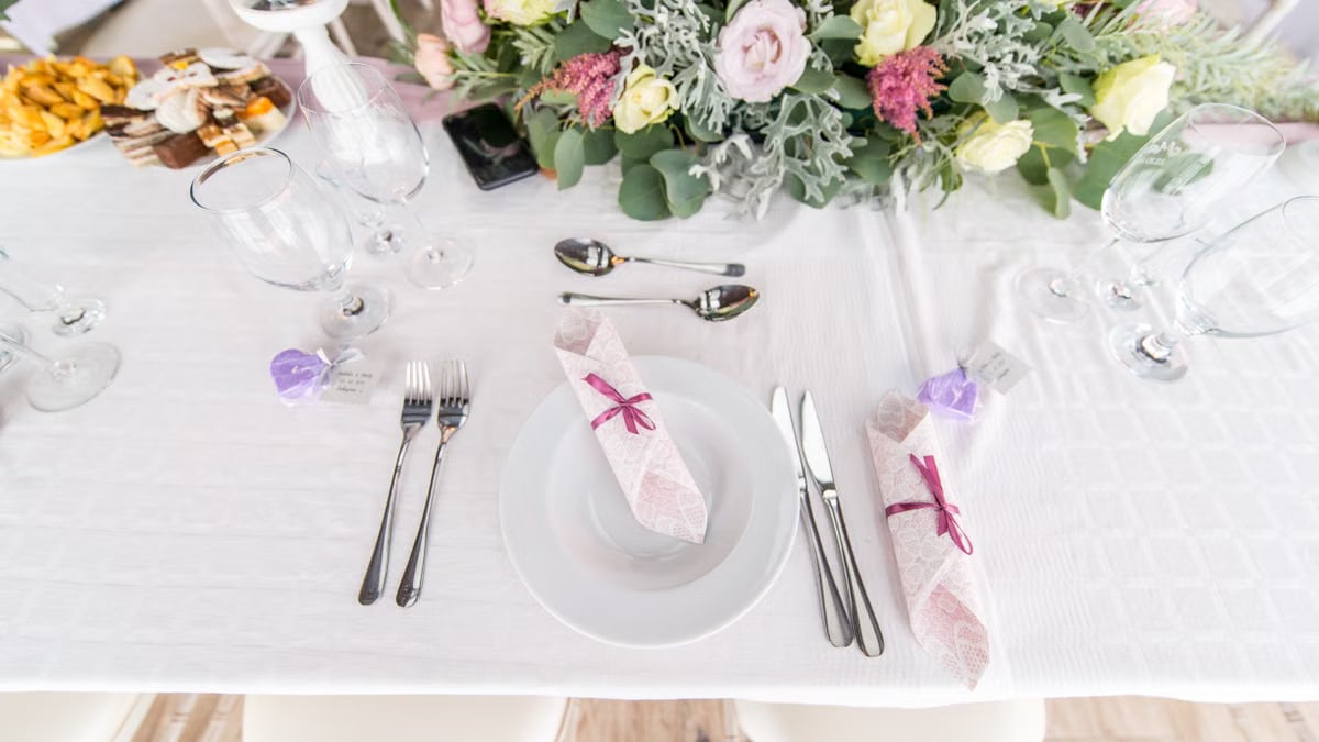 Elegant table setting with floral centerpiece, cutlery, and glasses at a wedding or event.